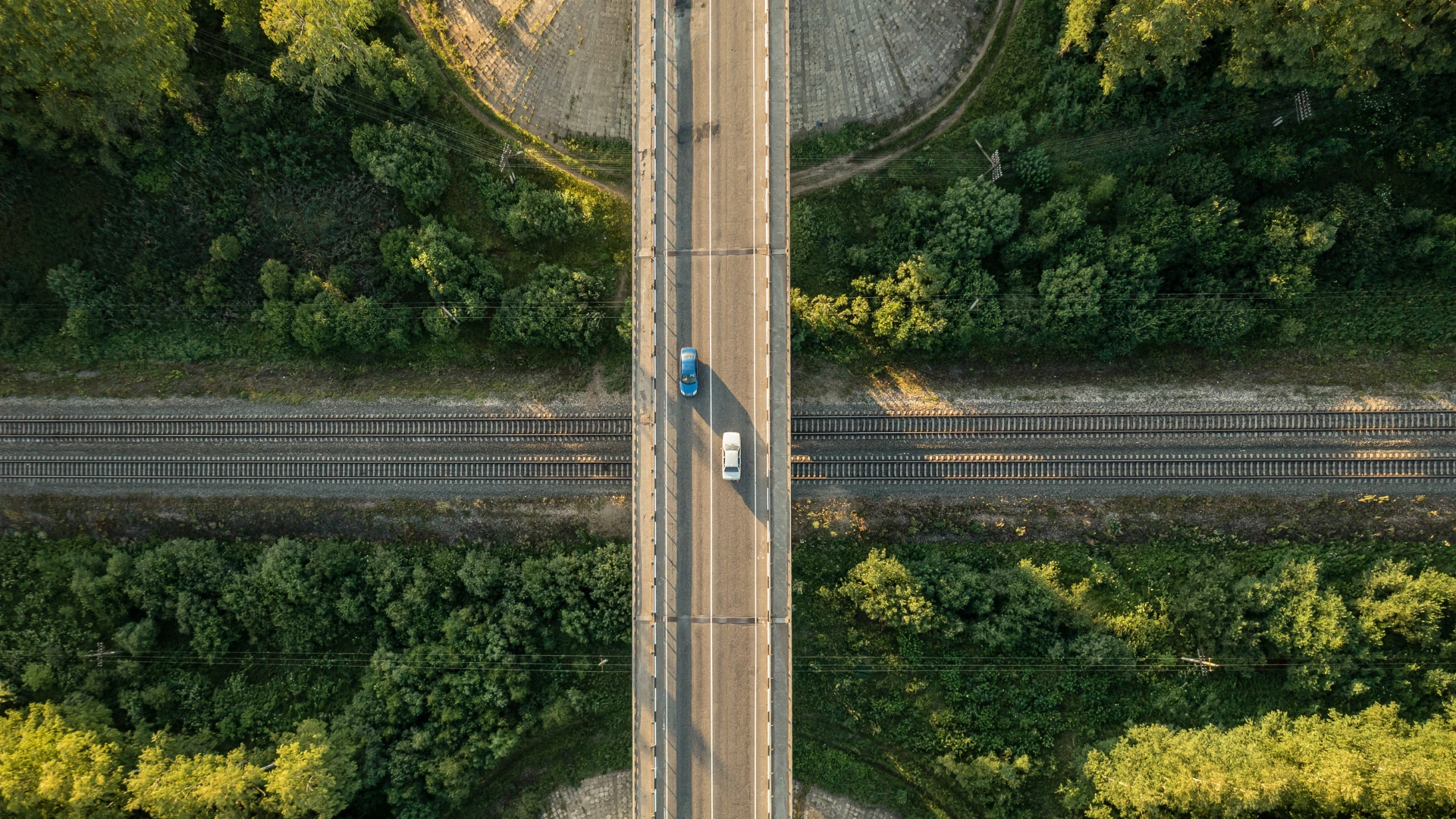 Vista aérea de uma ponte a atravessar uma área verde, rodeada de vegetação.
