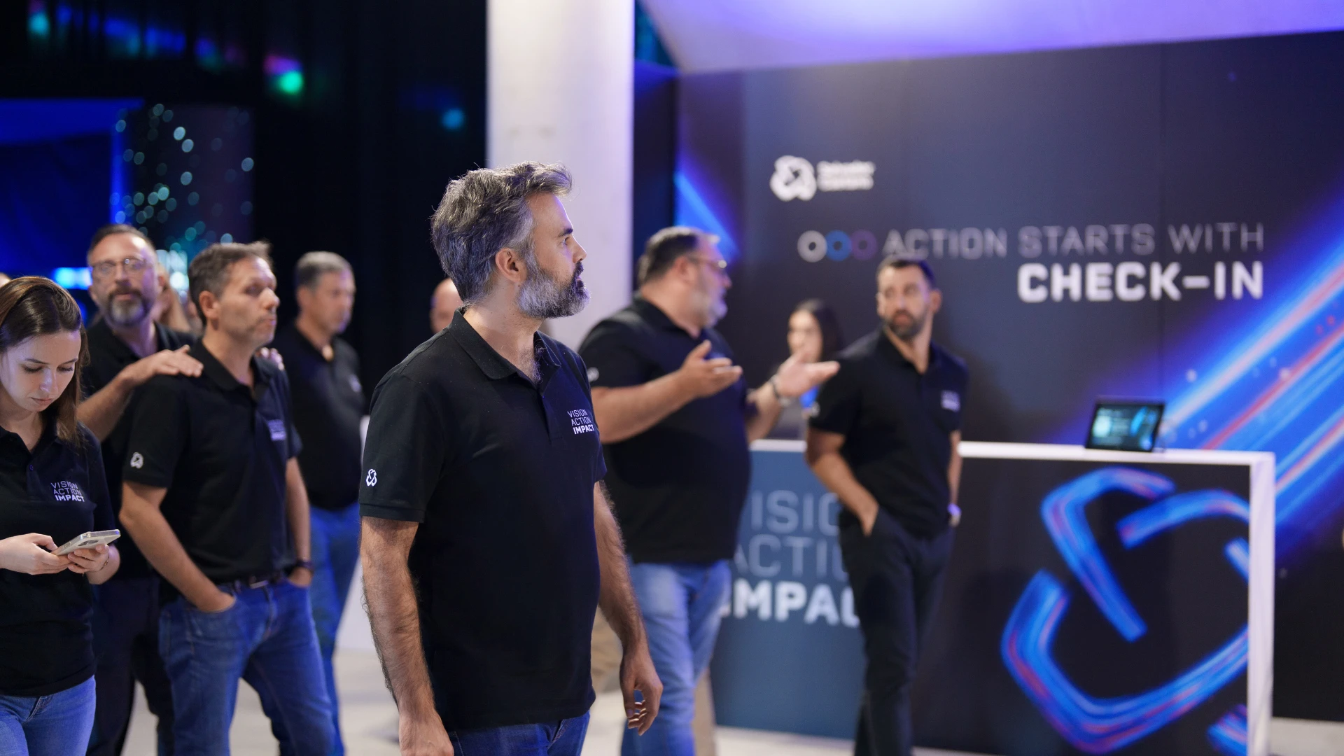 Colaboradores reunidos num espaço de evento junto a uma área de check-in.