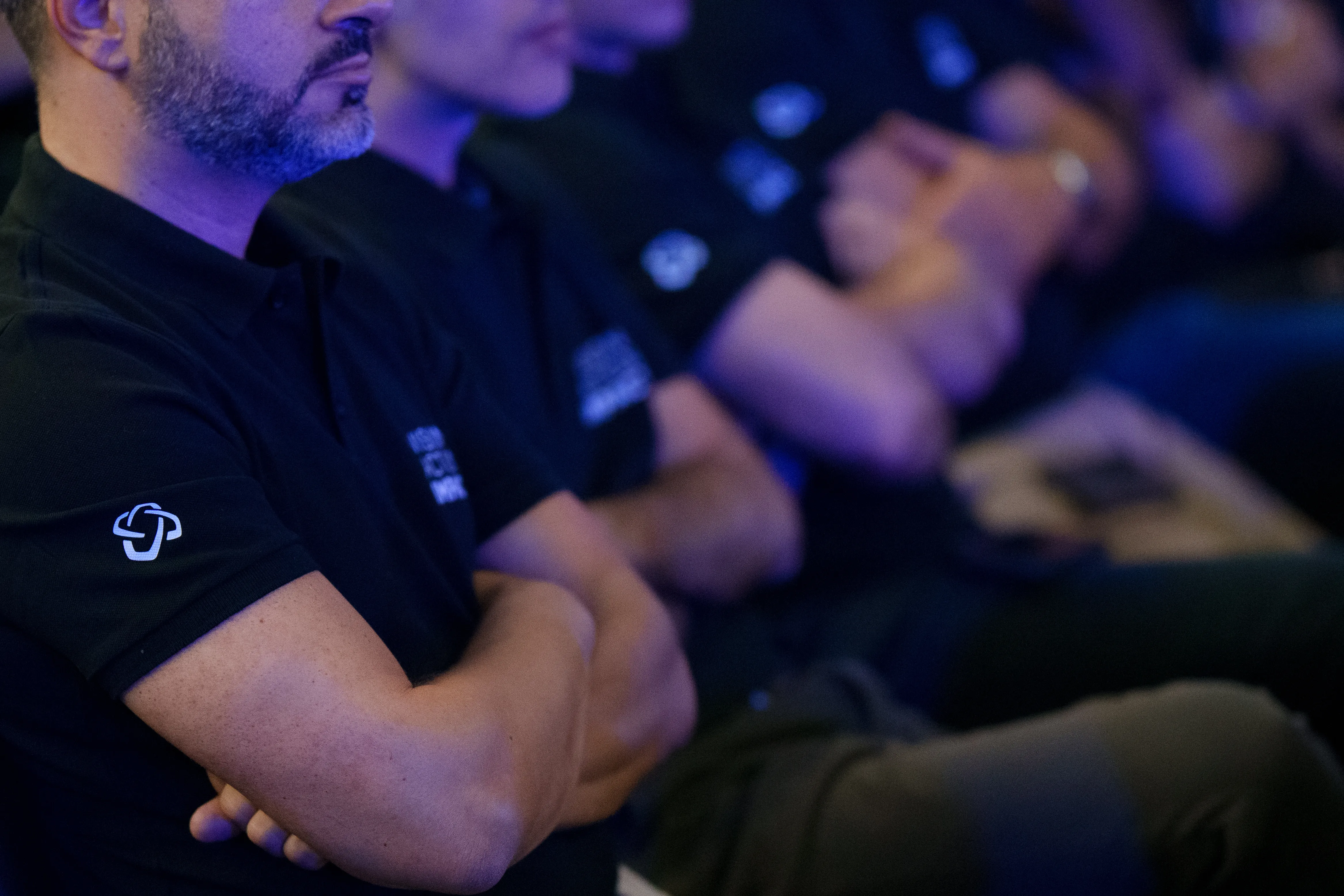 Colaboradores sentados lado a lado em contexto de evento corporativo, vistas em detalhe.