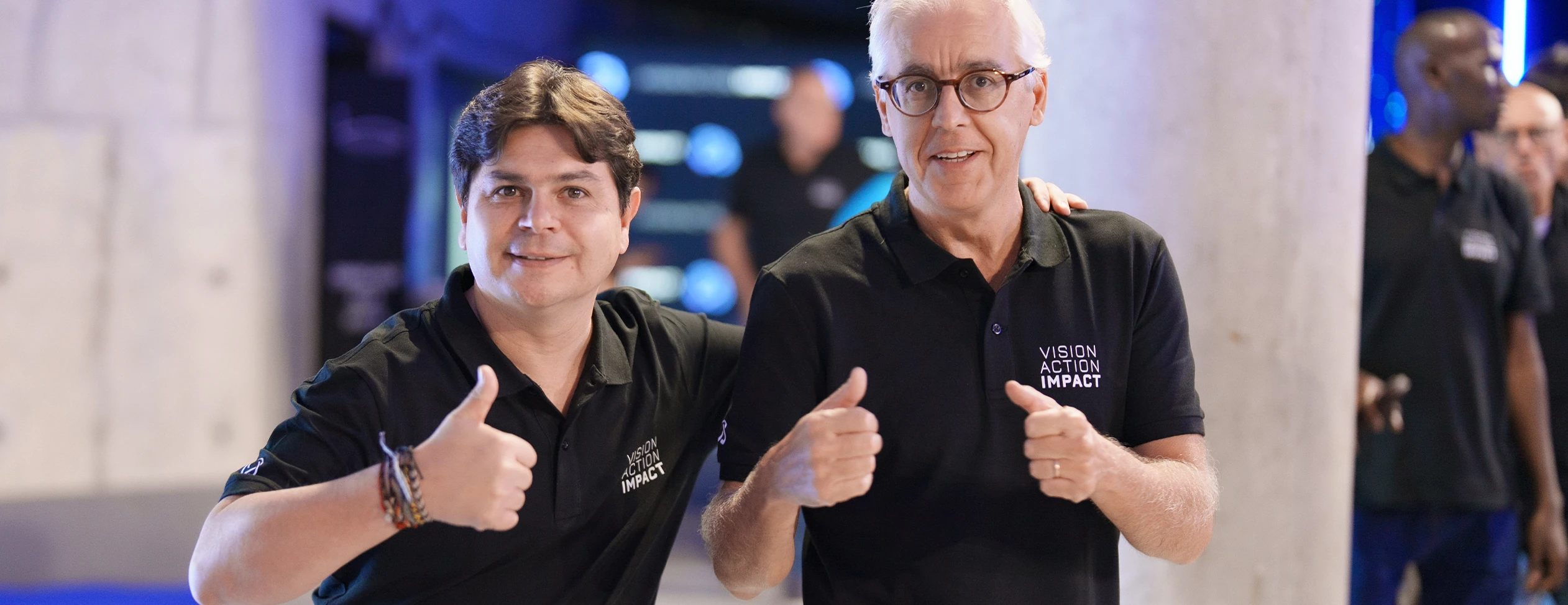 Dois colaboradores num evento corporativo, a posar para fotografia em espaço interior.