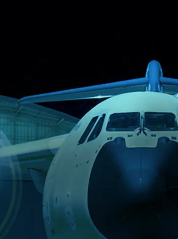 Detalhe da frente de um avião, com cockpit e fuselagem visíveis, em ambiente de baixa luminosidade.