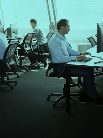 Colaboradores nonescritório, sentados em postos de trabalho com computadores.