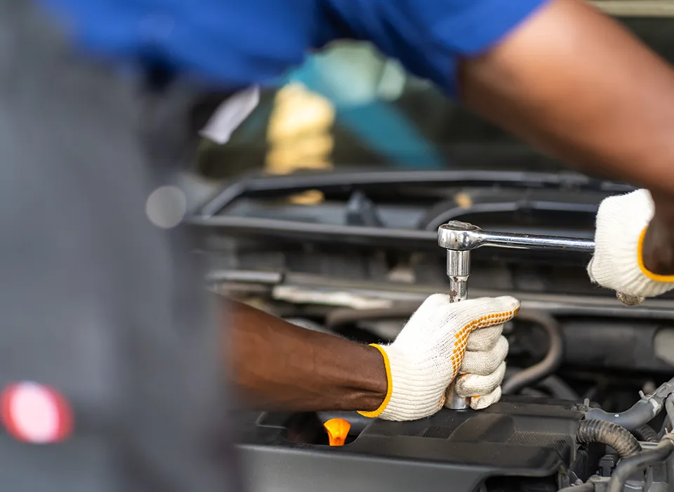 Mechanic repairing the engine with a screwdriver in his hand