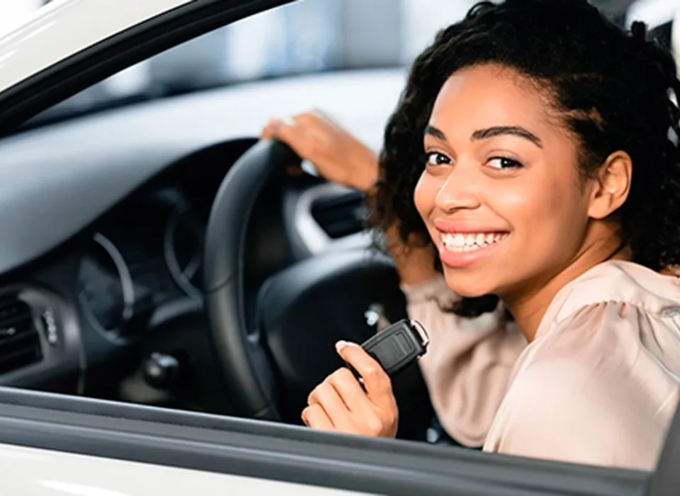 A person smiling inside their car