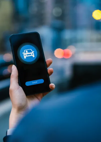 Uma mão a segurar um smartphone que mostra uma aplicação de transporte ou carro, com o ícone de um carro e um botão de "Cancelar".